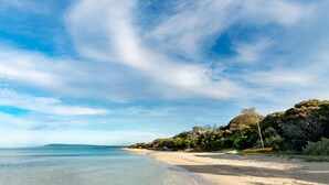 A beach with clear water, a sandy shore, and a small boat. - Boathouse Resort Studios & Suites (Blairgowrie)