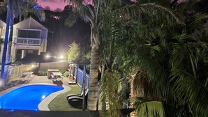 A pool area with a house in the background. - Boathouse Resort Studios & Suites (Blairgowrie)