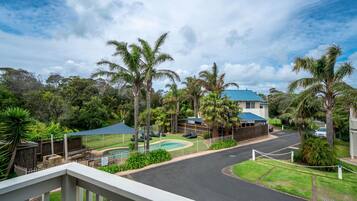 A residential area with a pool, palm trees, and a house with a blue roof.