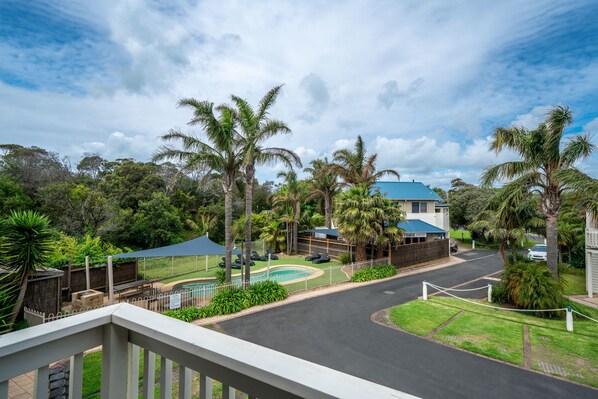 A residential area with a pool, palm trees, and a house with a blue roof. - Boathouse Resort Studios & Suites (Blairgowrie)