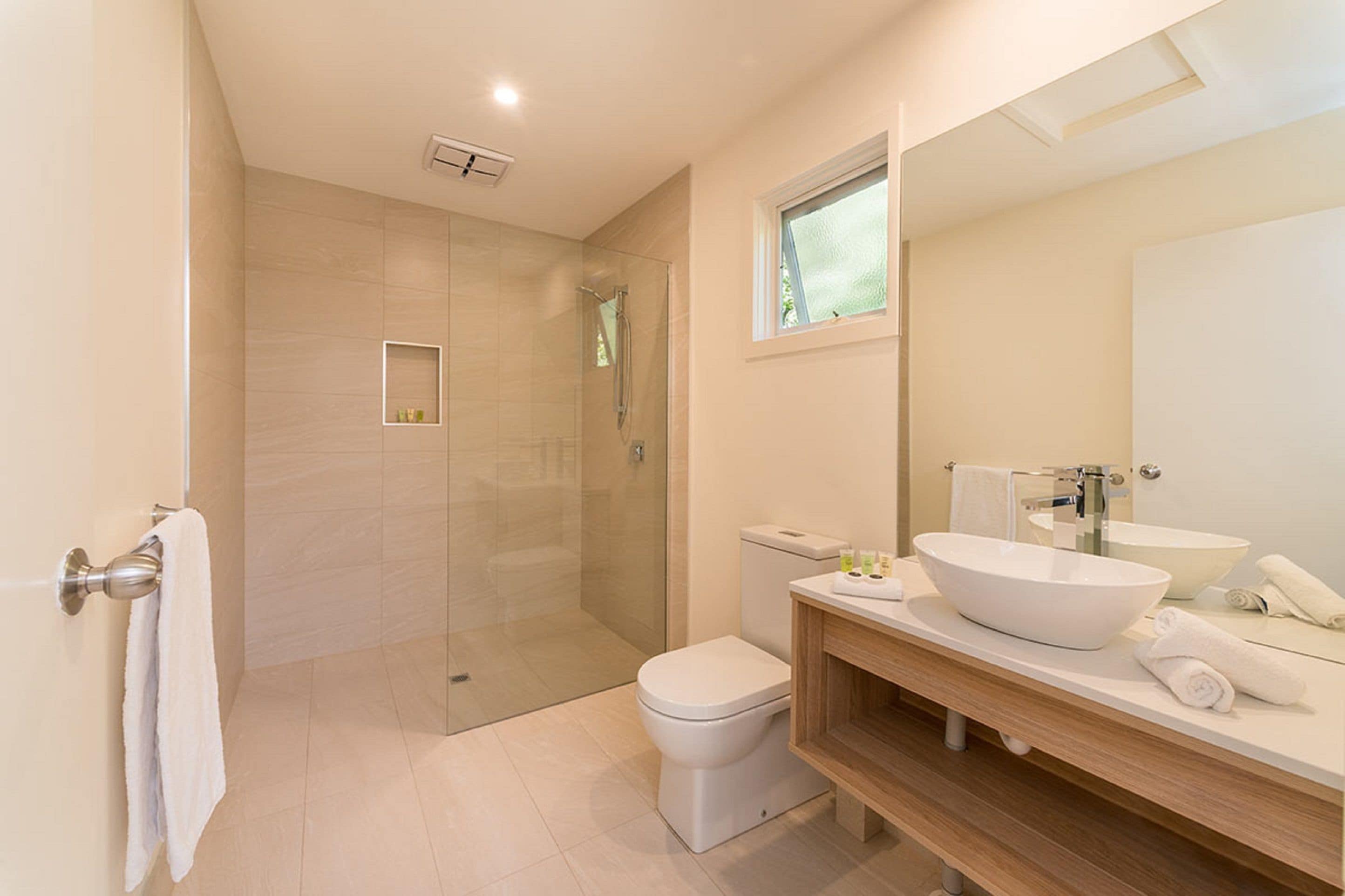 A modern bathroom with a glass-enclosed shower, a toilet, and a large sink with a vessel basin.