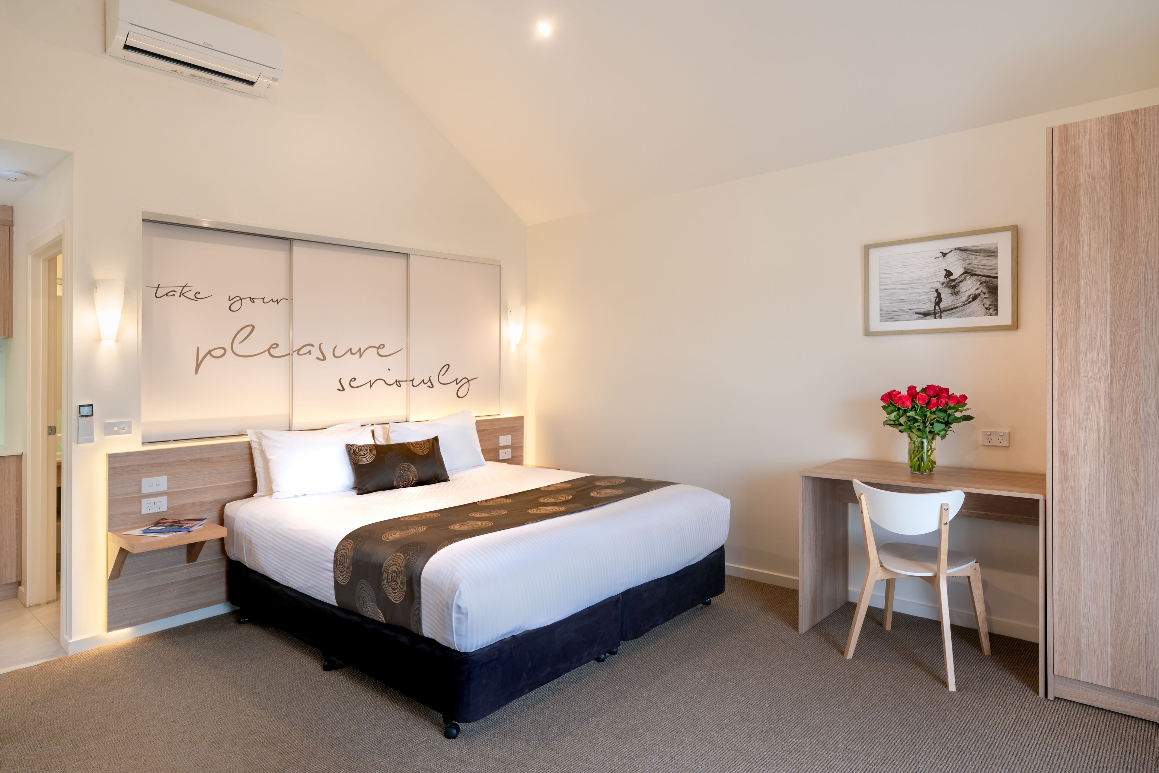 Une chambre bien rangée, avec un lit, des tables de chevet, un bureau et une chaise.