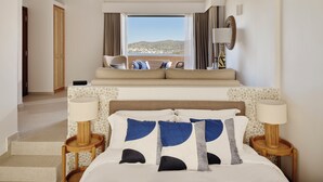 A hotel room with a bed, two bedside tables, a sofa, a view of the sea, and a staircase leading to another room. - Angelina Aegina Boutique Escape (Aegina)