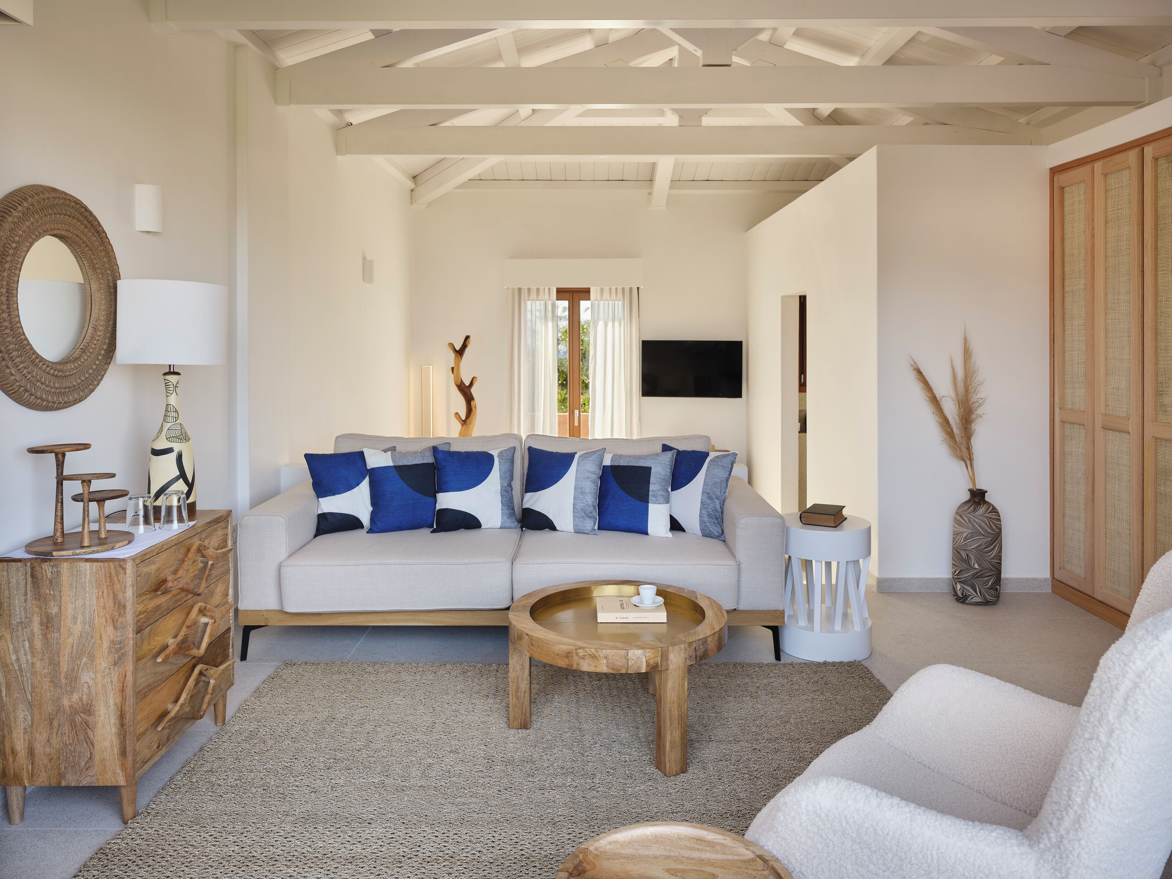 A living room with a sofa, coffee table, wooden sideboard, and a TV.