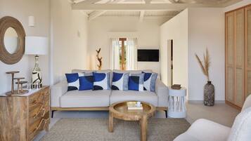 A living room with a sofa, coffee table, wooden sideboard, and a TV.