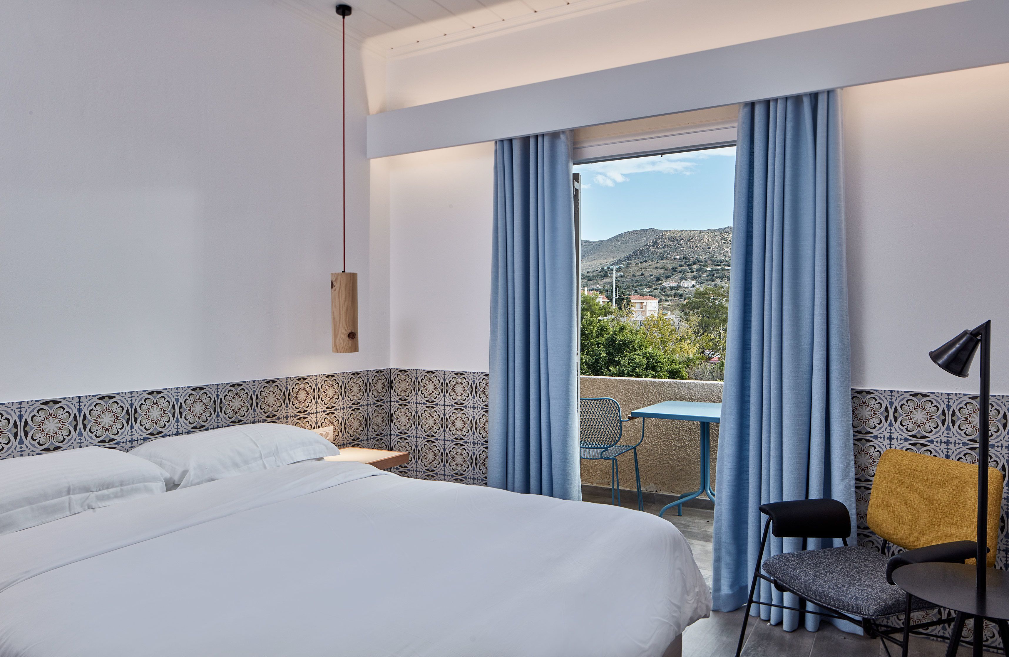 Une chambre d’hôtel équipée d’un lit, d’un bureau, d’une chaise et offrant une vue sur un paysage montagneux grâce à une grande fenêtre.