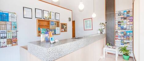 A reception area with a counter, framed certificates, a clock, and a bookshelf with magazines.