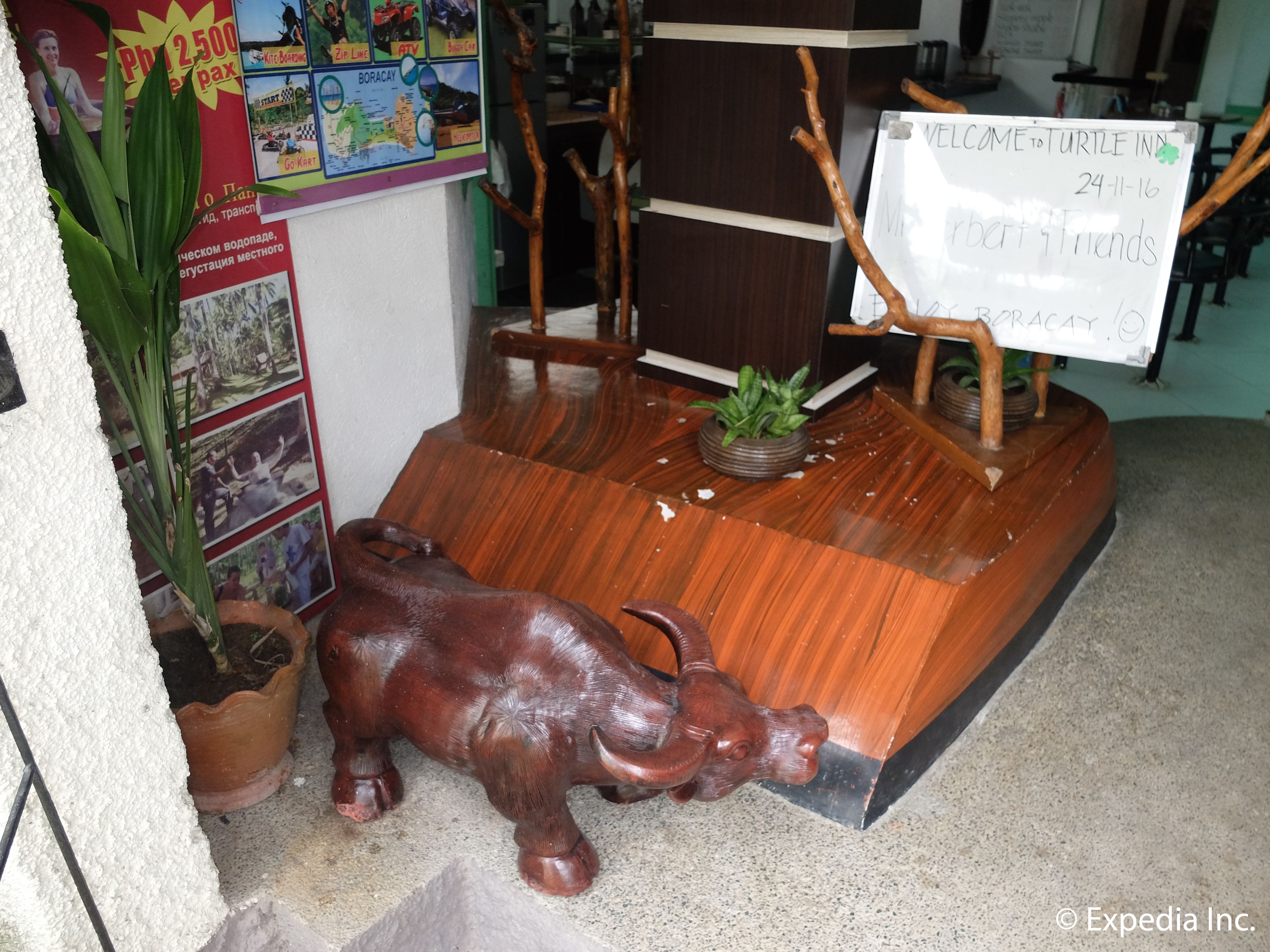 A wooden bull sculpture in a lobby area with a signboard and a plant.