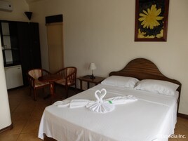 Habitación de hotel con cama, escritorio, silla, lámpara y un cuadro en la pared.