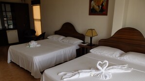 A hotel room with two beds, each with white linens and heart-shaped towels. There is a nightstand with a lamp and a painting on the wall. - Turtle Inn Resort (Boracay Island)