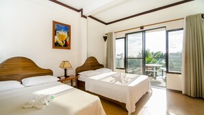 A hotel room with two beds, a painting, a nightstand, a lamp, and a balcony with a view. - Turtle Inn Resort (Boracay Island)
