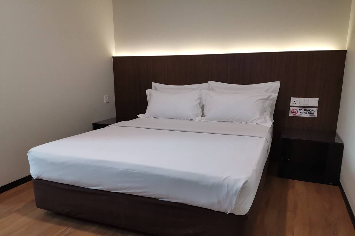 A neatly made bed with white linens in a hotel room.