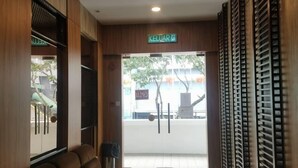 A reception area with a wooden reception desk, a brown sofa, and a sign reading "KELUAR". - Hotel Holiday (Kota Kinabalu)