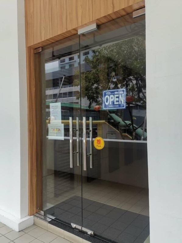 A glass door with a 'YES, Welcome Open' sign, a 'PUSI' sticker, and a metal handle. - Hotel Holiday (Kota Kinabalu)