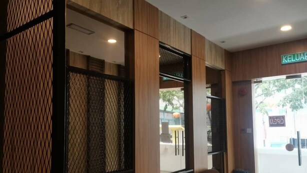 A reception area with a seating area, wooden paneling, and a view of the street outside. - Hotel Holiday (Kota Kinabalu)