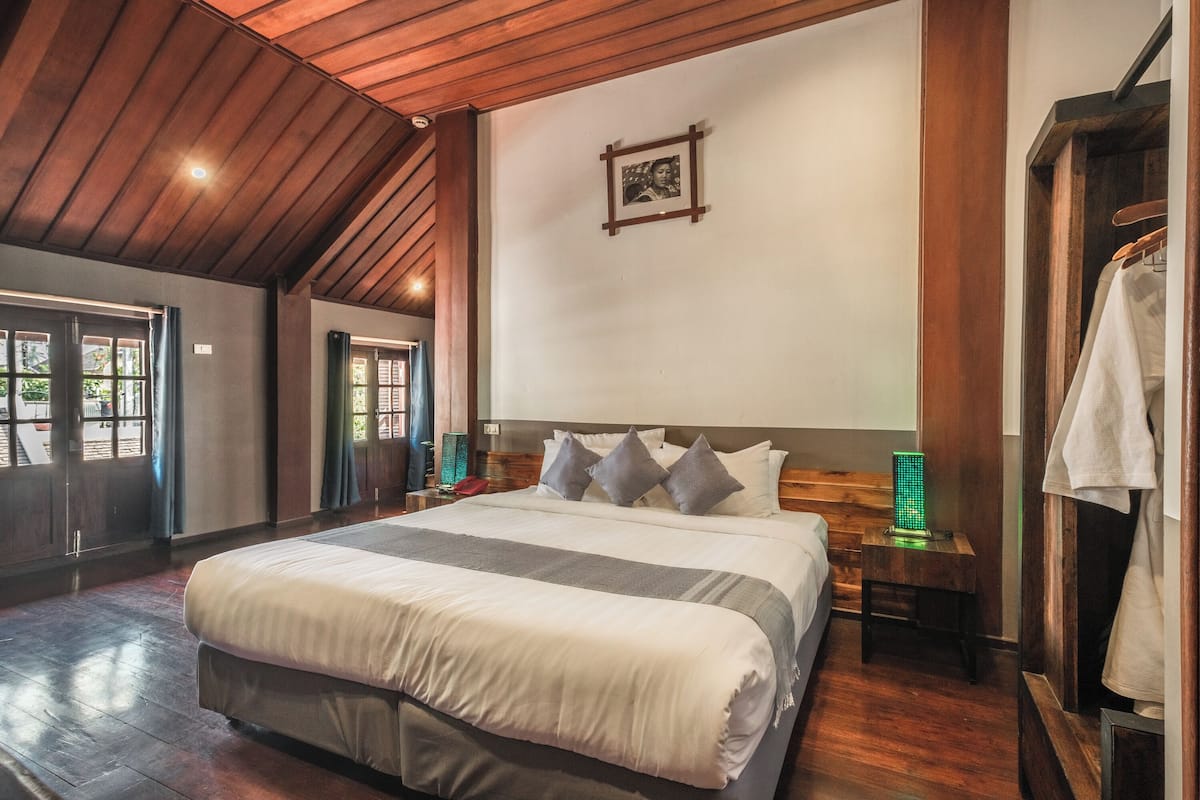 Une chambre spacieuse avec un grand lit, un plafond en bois et un tableau encadré au mur.