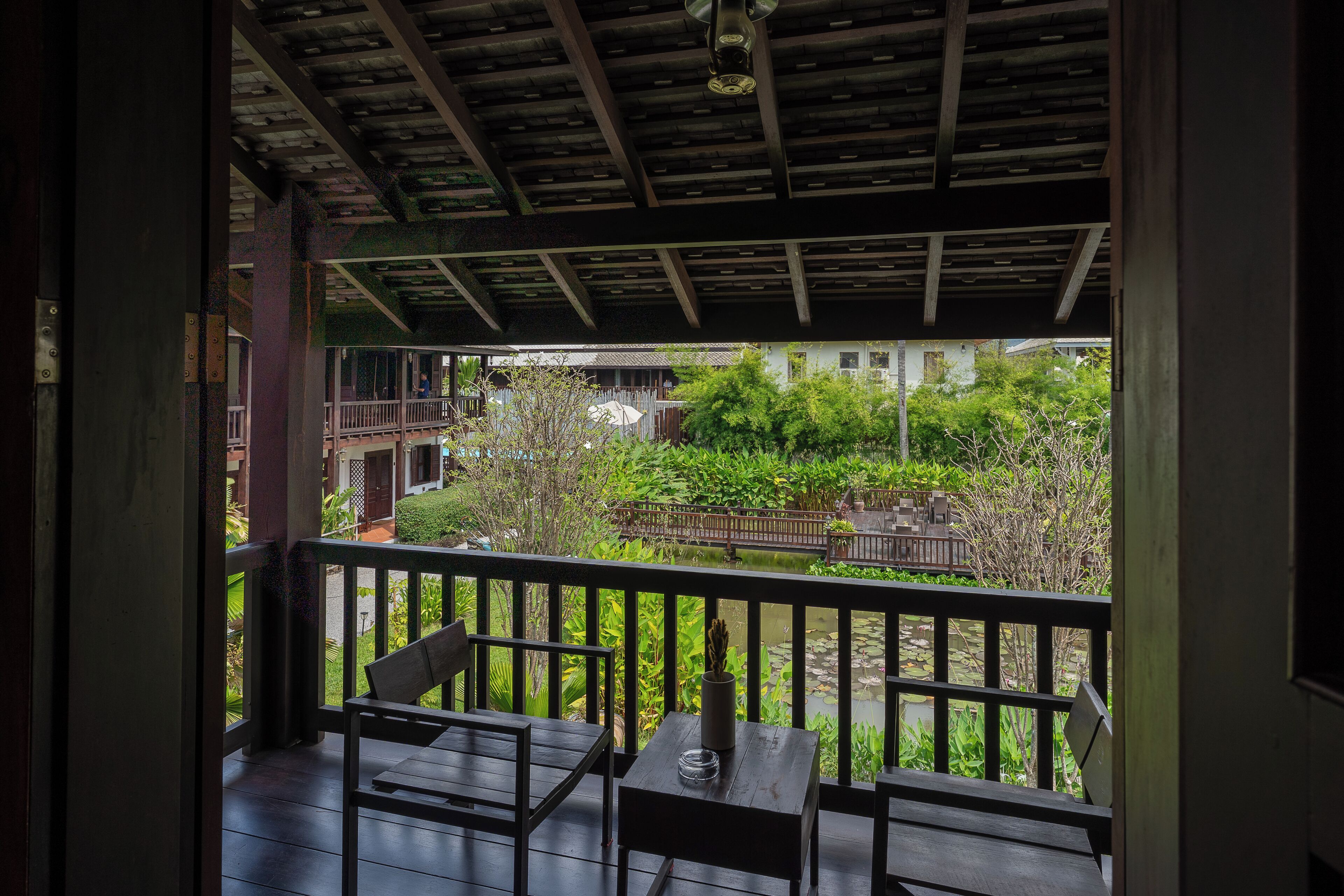 Ein hölzerner Balkon mit Blick auf einen Garten und Gebäude im Hintergrund.