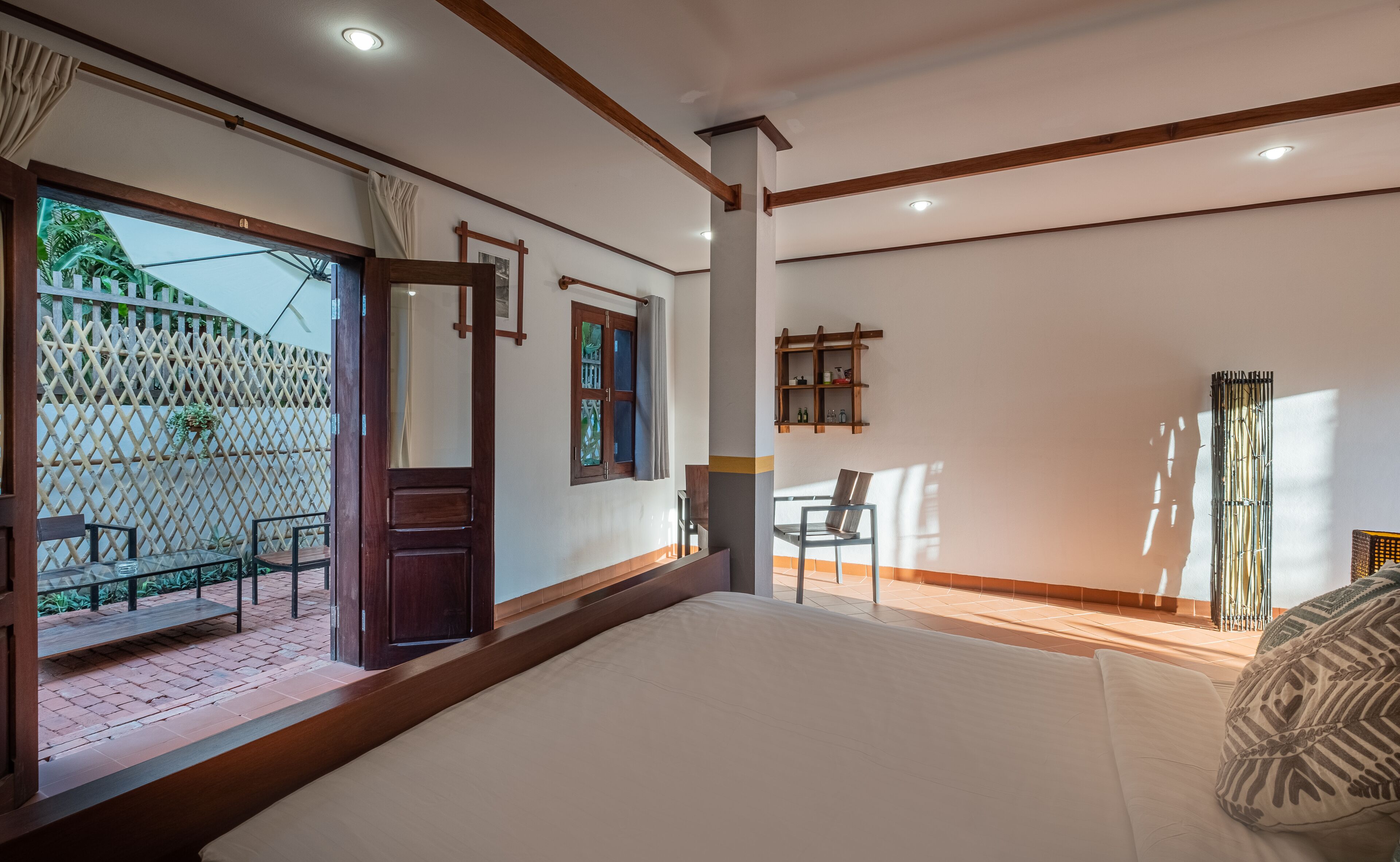 A spacious bedroom with a large bed, a wooden door, a small table, and a chair.