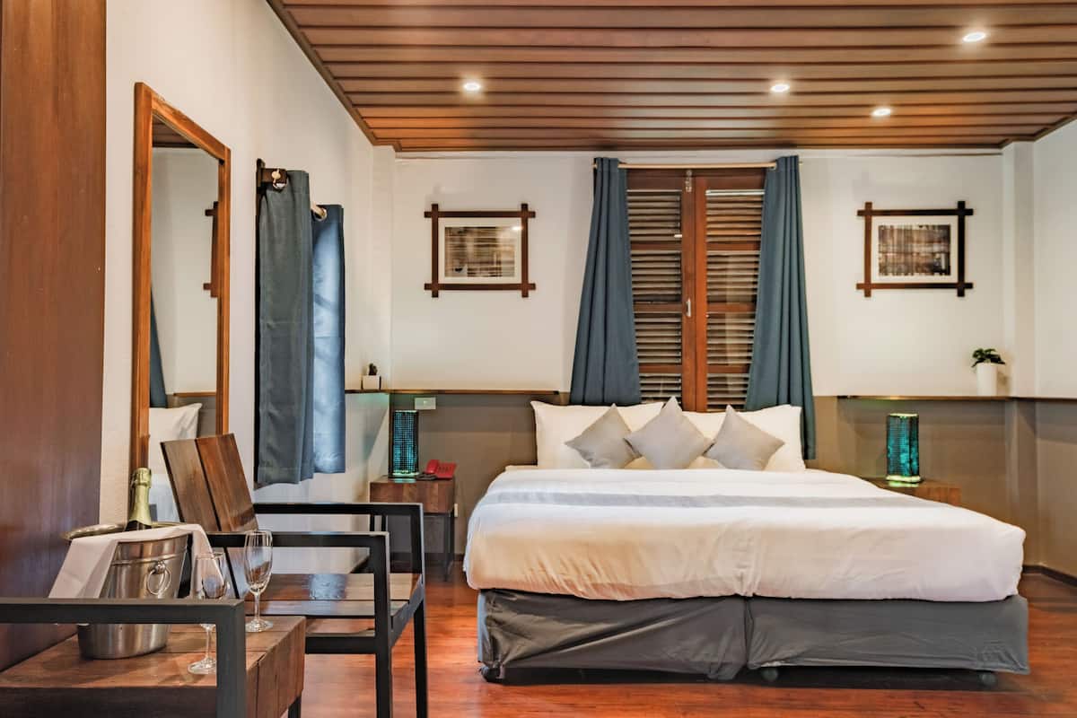 Une chambre d’hôtel moderne avec un grand lit, un plafond en bois et deux tables de chevet équipées de lampes.