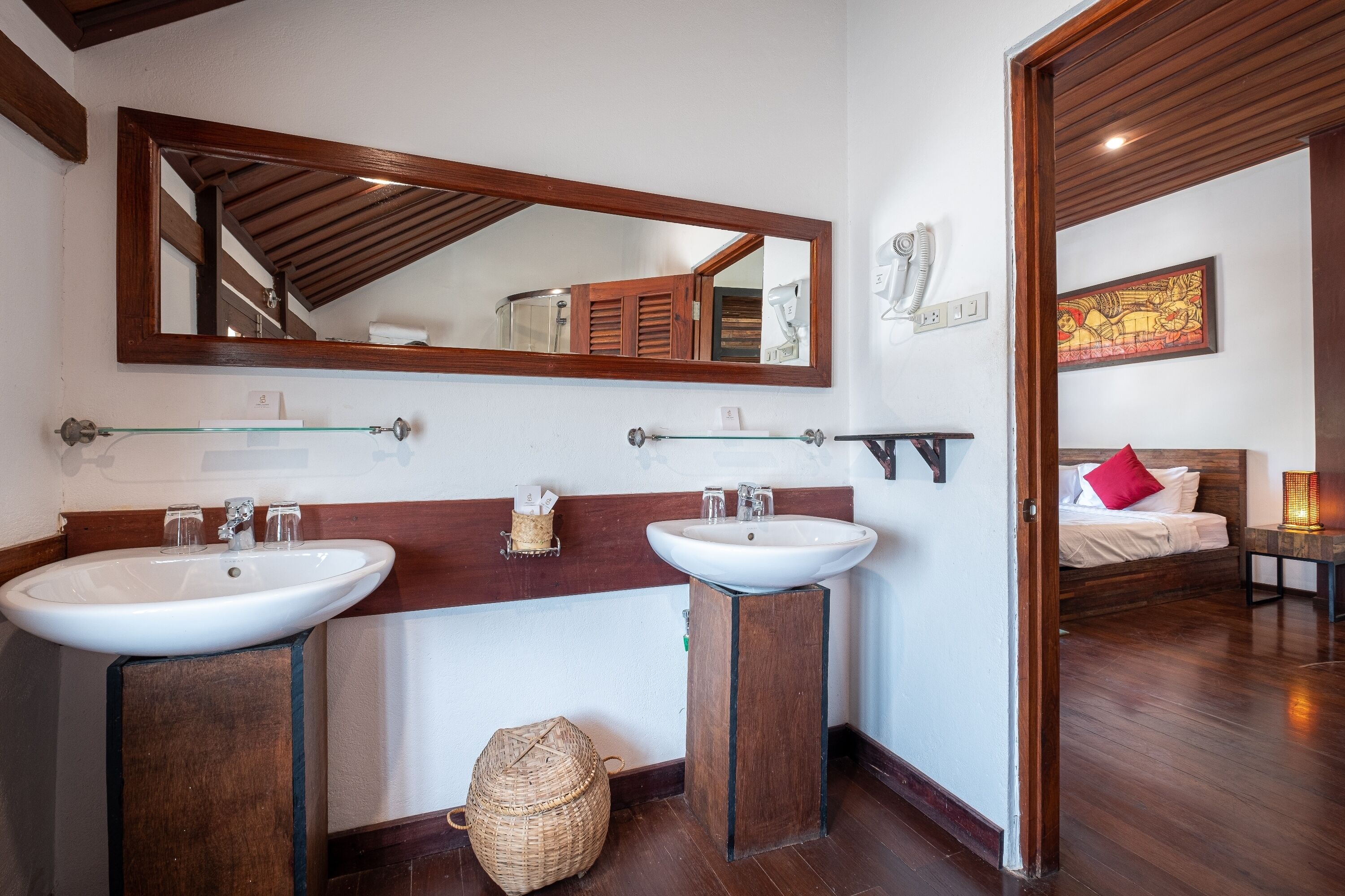 A bathroom with two sinks, a large mirror, and a wooden vanity.