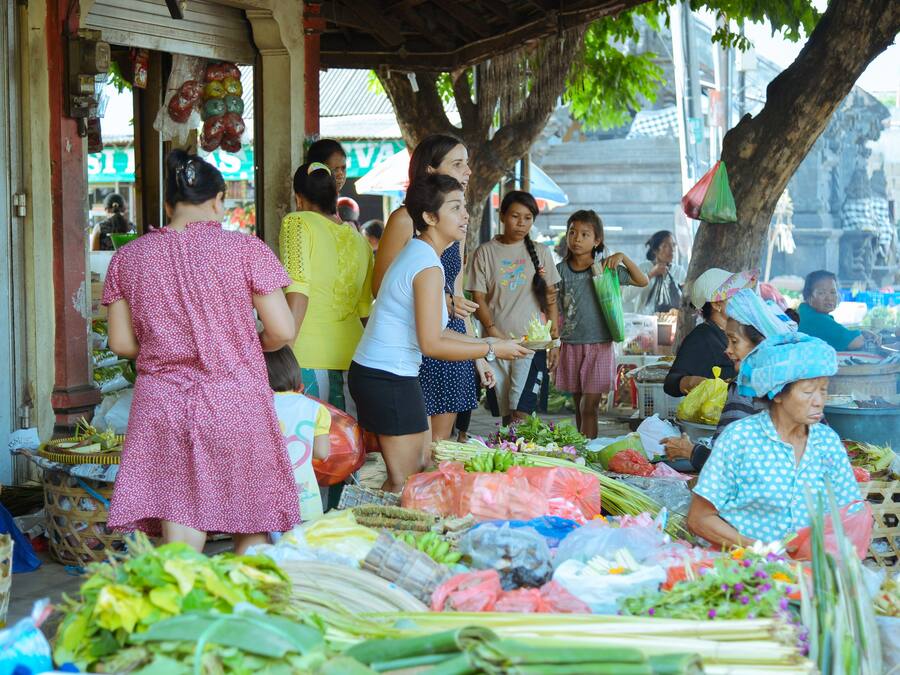 Mercado ao ar livre movimentado com diversos pontos de venda de produtos frescos e artigos.