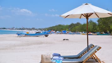 Vlak bij het strand, wit zand, ligstoelen aan het strand, parasols
