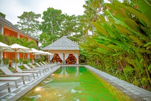 Relax by the serene pool surrounded by lush greenery and comfortable lounge chairs.