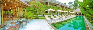 Relax by the pool surrounded by lush greenery and shaded seating.