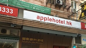 Un hôtel avec une enseigne indiquant « applehotel.hk » et un restaurant avec une enseigne dans une langue étrangère.