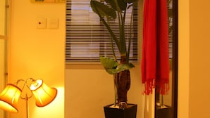 Un couloir avec un plancher en bois, une plante en pot, une lampe et un miroir.