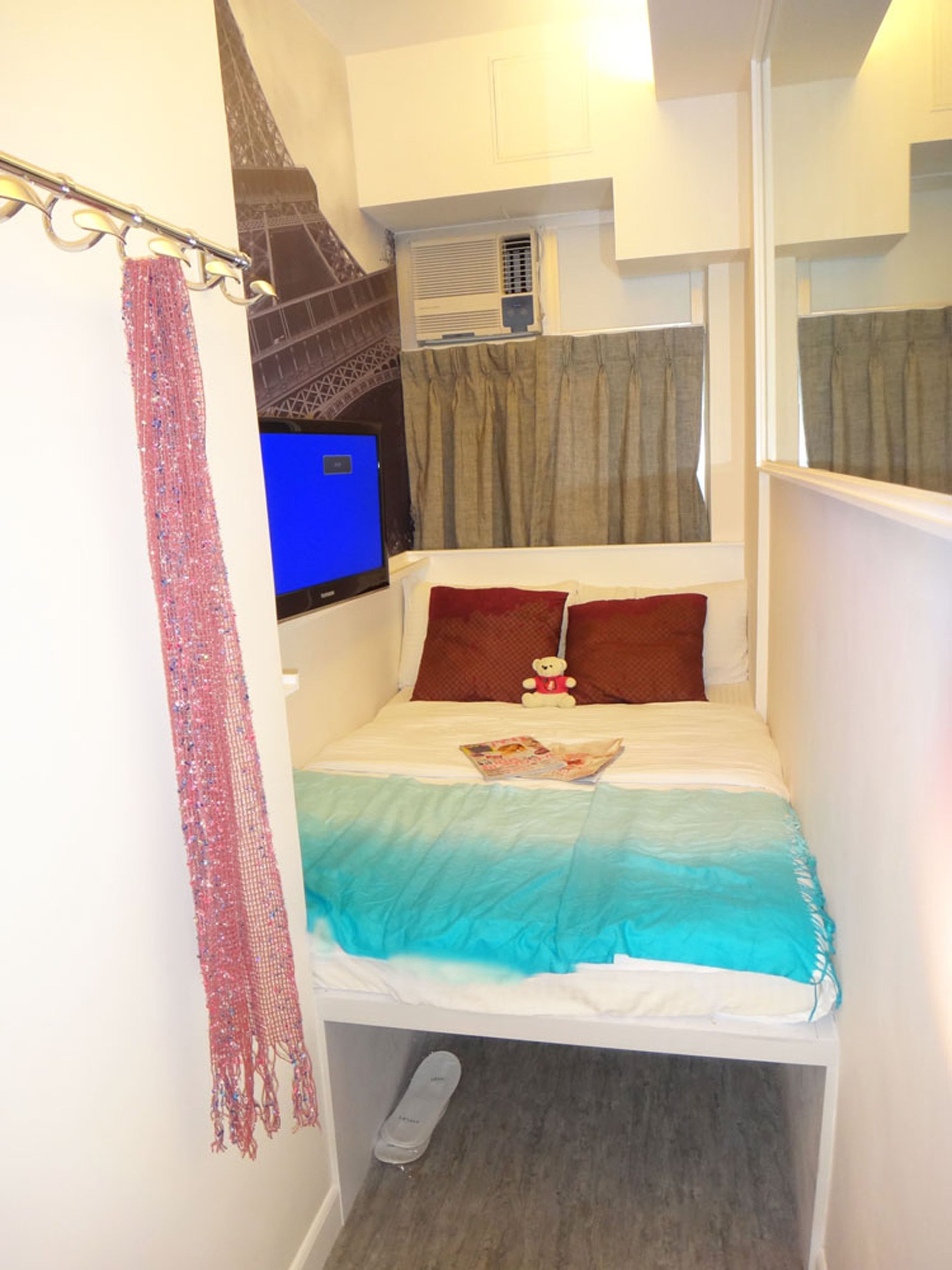 A small, narrow room with a bed, a window, and a curtain.