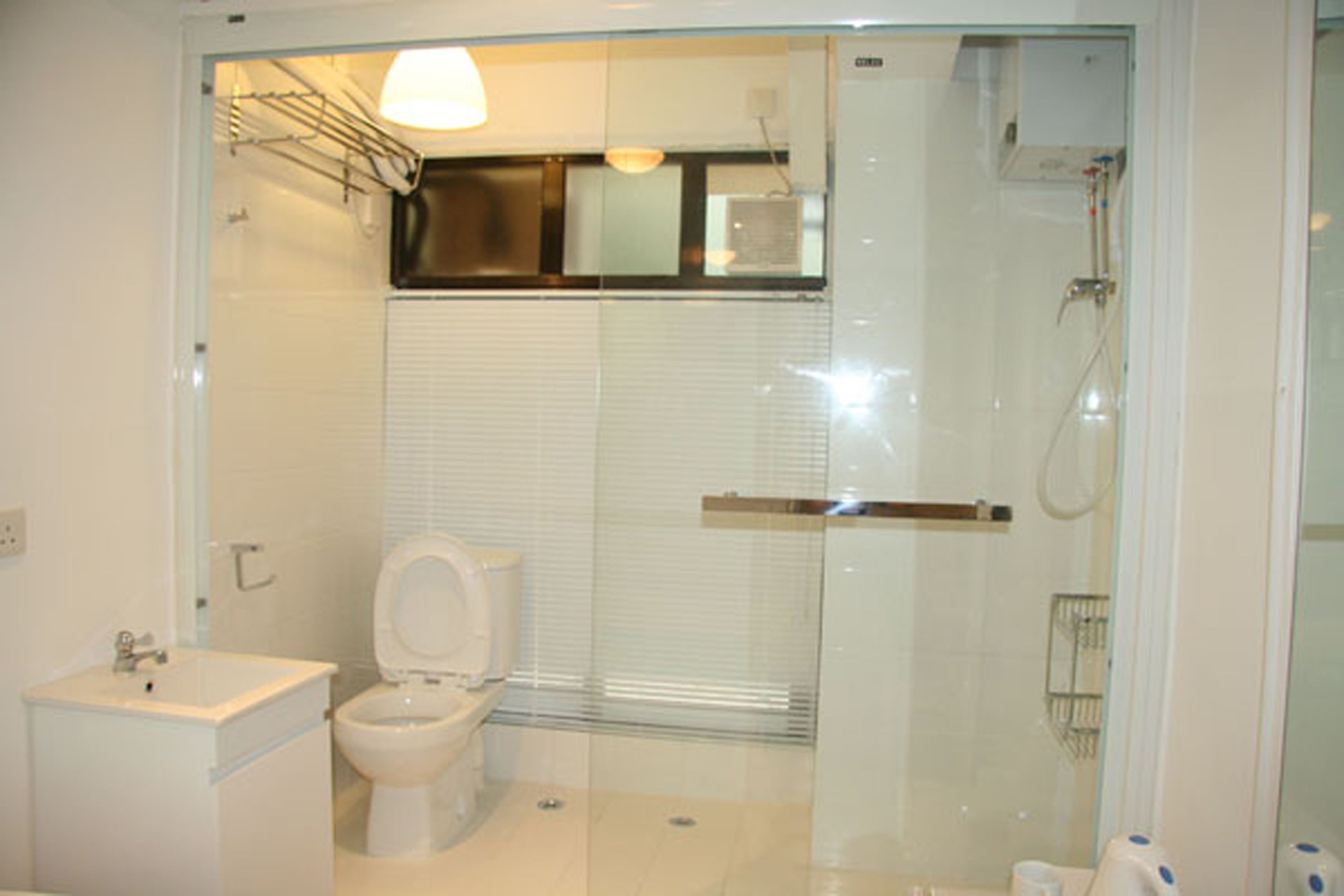 A modern bathroom with a glass-enclosed shower, a toilet, and a sink.