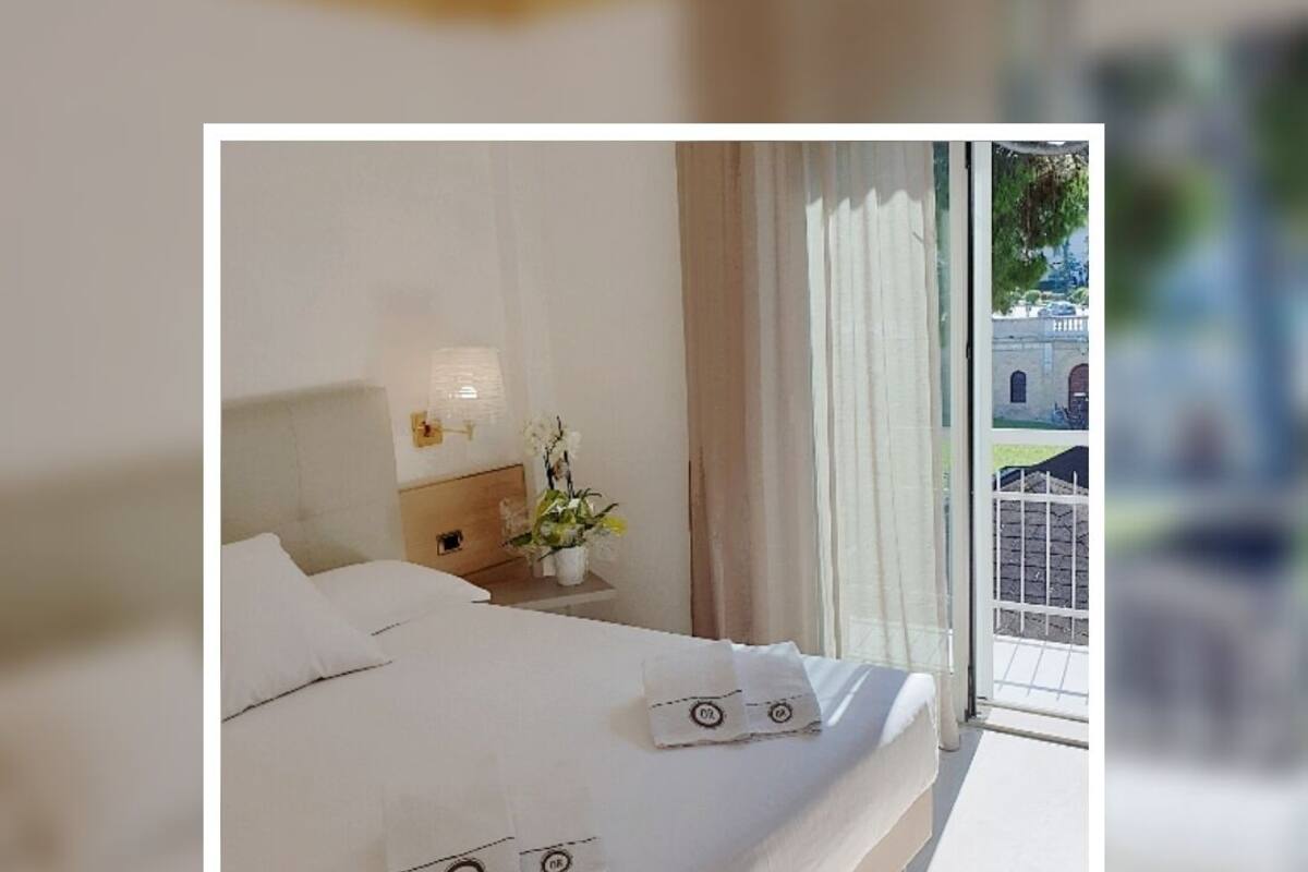 A hotel room with a bed, a nightstand with a lamp, and a window with curtains.