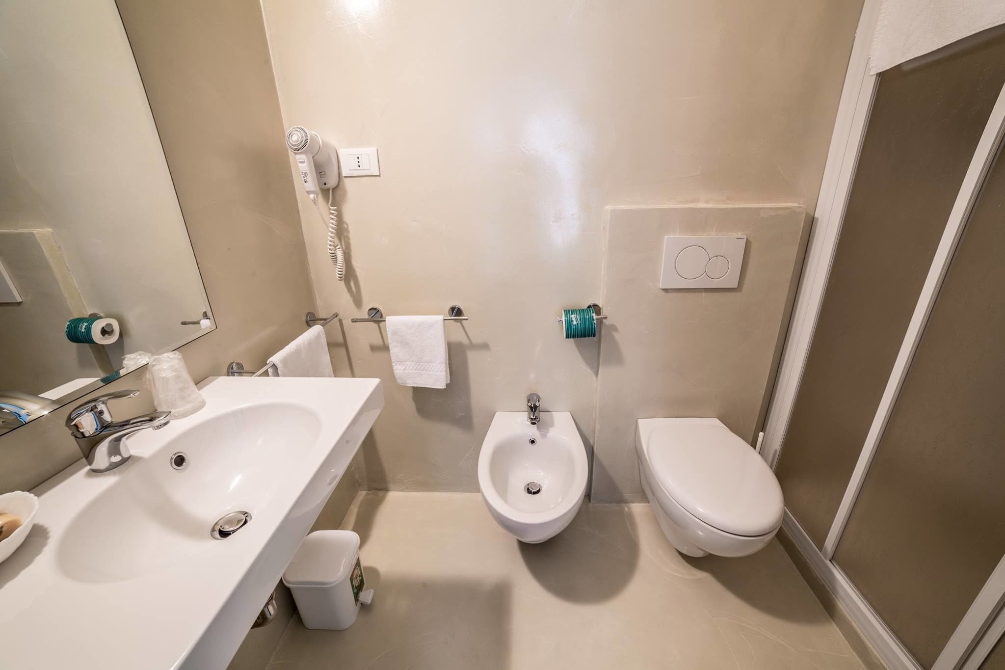 A bathroom with a sink, bidet, toilet, and a mirror.