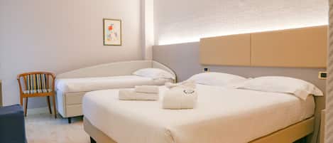 Una habitación de hotel con dos camas, una silla y una mesita.