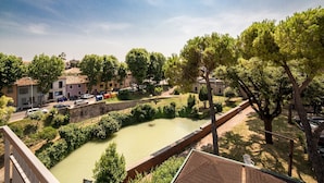 A riverside view with buildings, trees, and a bridge. - Hotel Augustus (Fano)