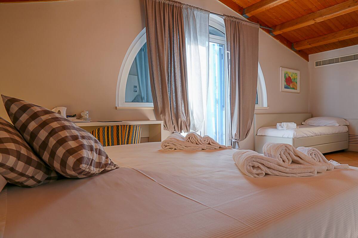 A hotel room with a bed, a desk, and a window with curtains.