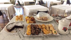 A marble counter with various pastries and desserts, including a cake, cookies, and a covered container. - Hotel Augustus (Fano)