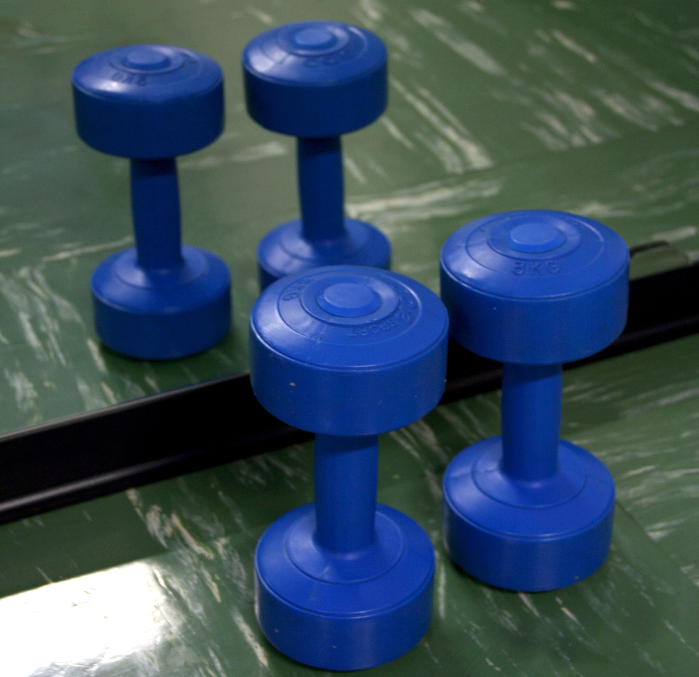 A set of blue dumbbells on a green surface.