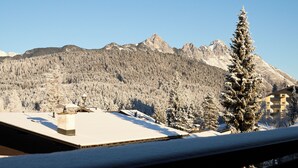 Paisaje nevado de montañas con un edificio de techos planos y chimenea.