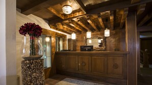 Un mostrador de recepción de madera con un jarrón de flores, un macetero de troncos de madera y lámparas colgantes.
