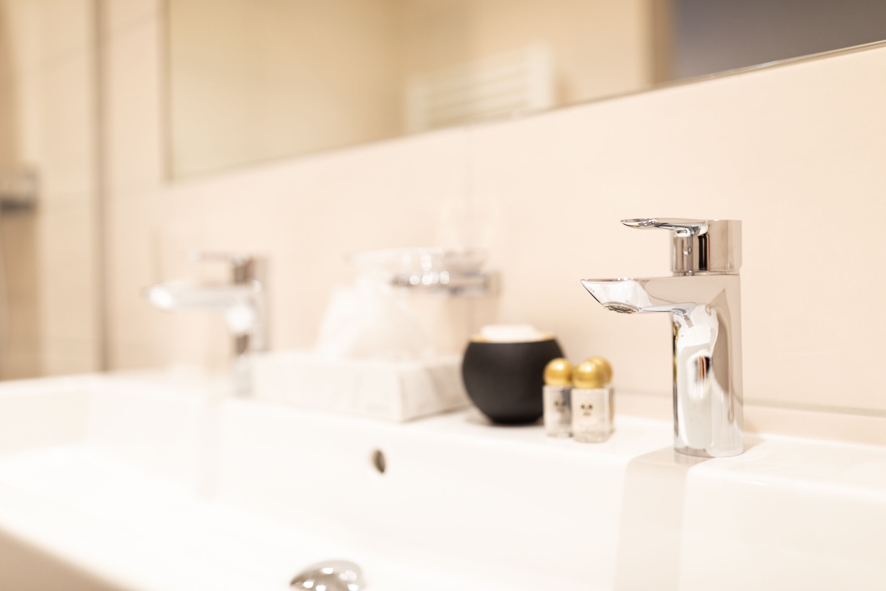 A modern bathroom with a white sink, chrome faucet, and a mirror.