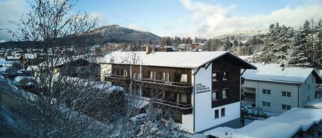 Ein Hotel mit verschneitem Dach, einem Balkon und einem Schild, das es als Hotel kennzeichnet.