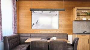 Un comedor moderno con una pared de madera, un cuadro grande enmarcado y un mueble de madera con copas.