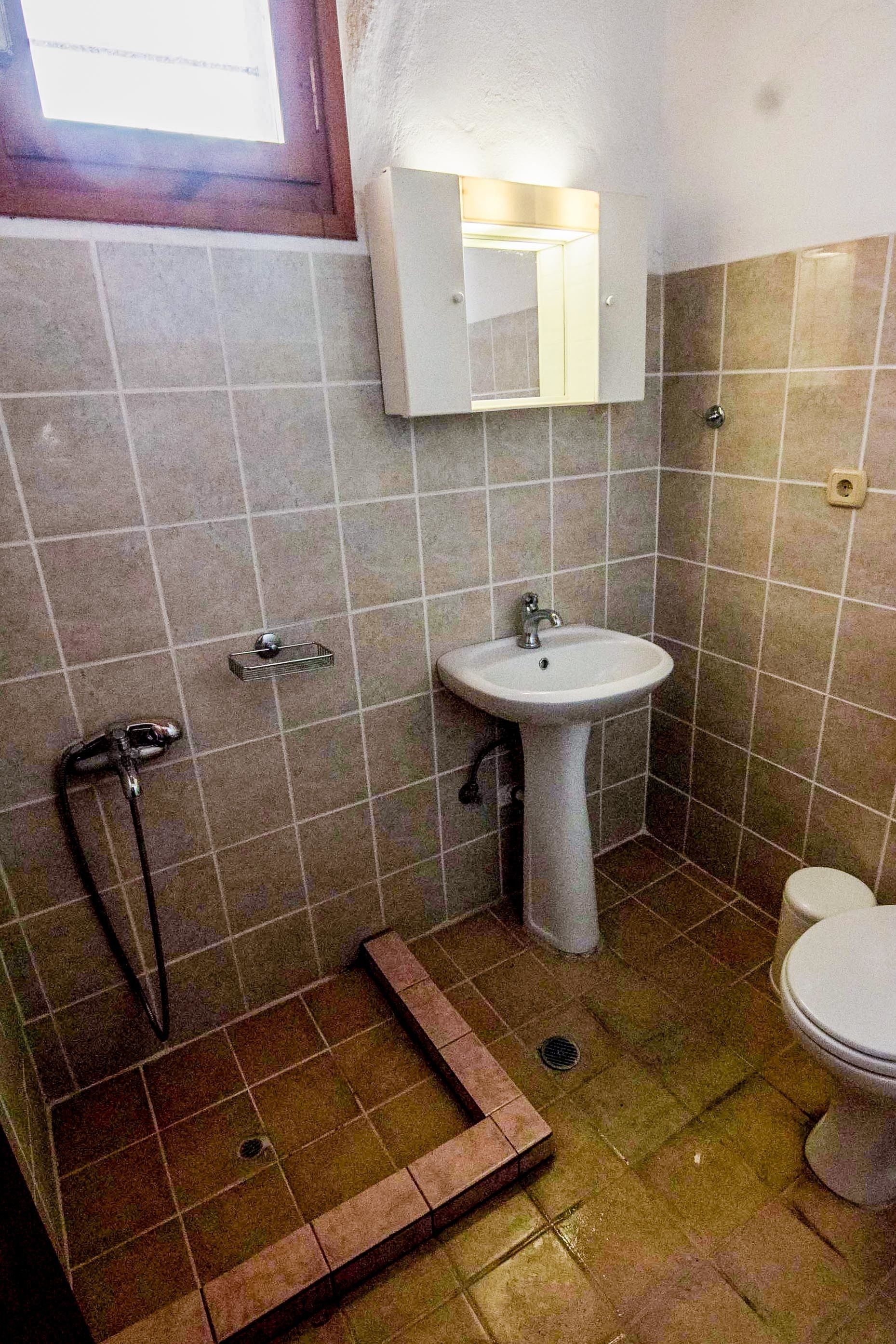 Egy fürdőszoba, amelyben mosdókagyló, tükör és WC található.
