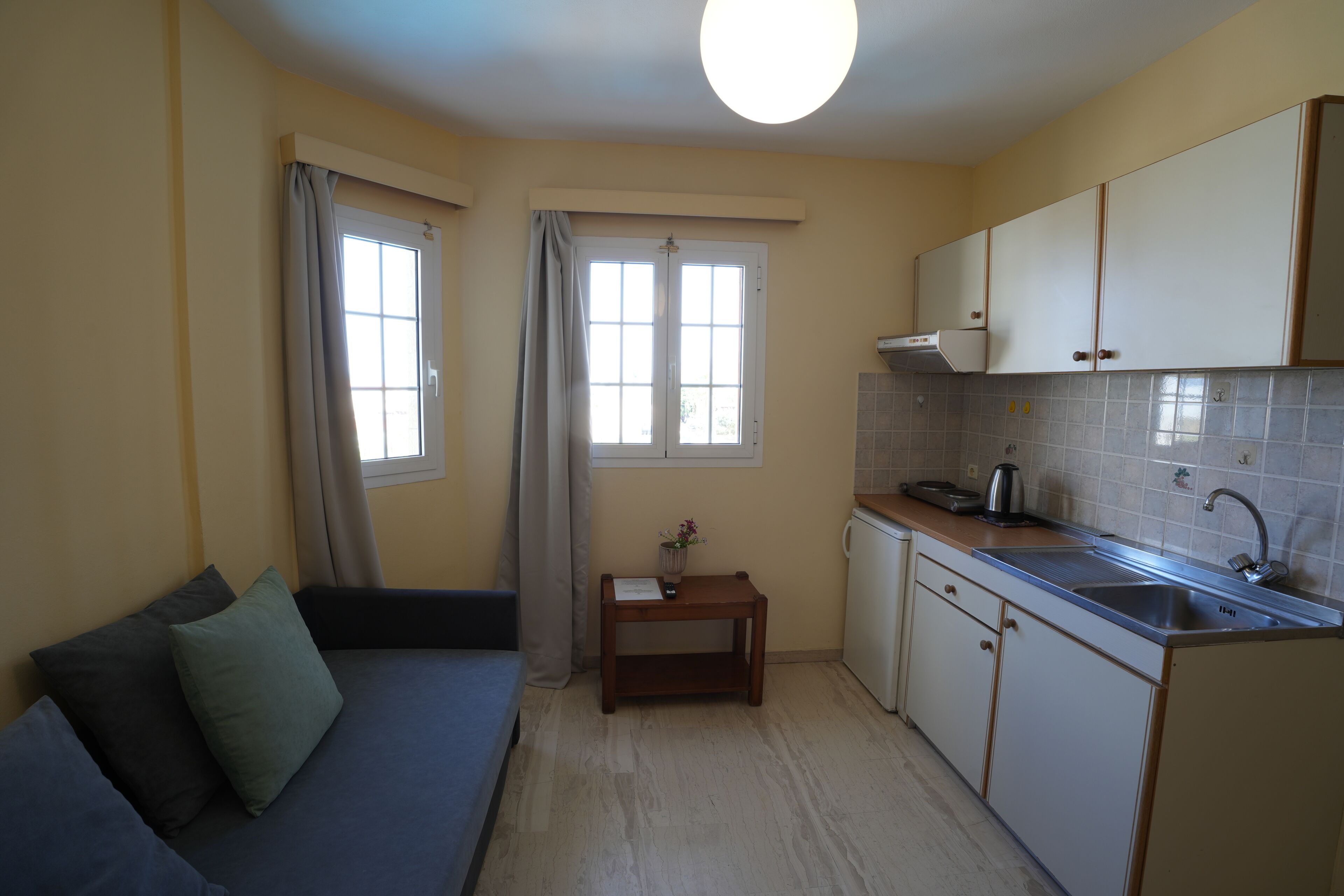 A compact kitchen with a built-in oven, a sink, and a small dining table.