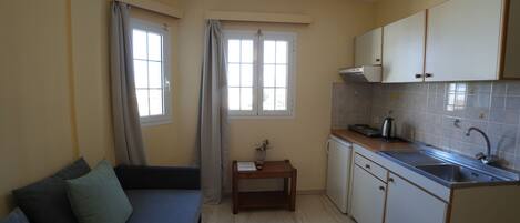 A compact kitchen with a built-in oven, a sink, and a small dining table.