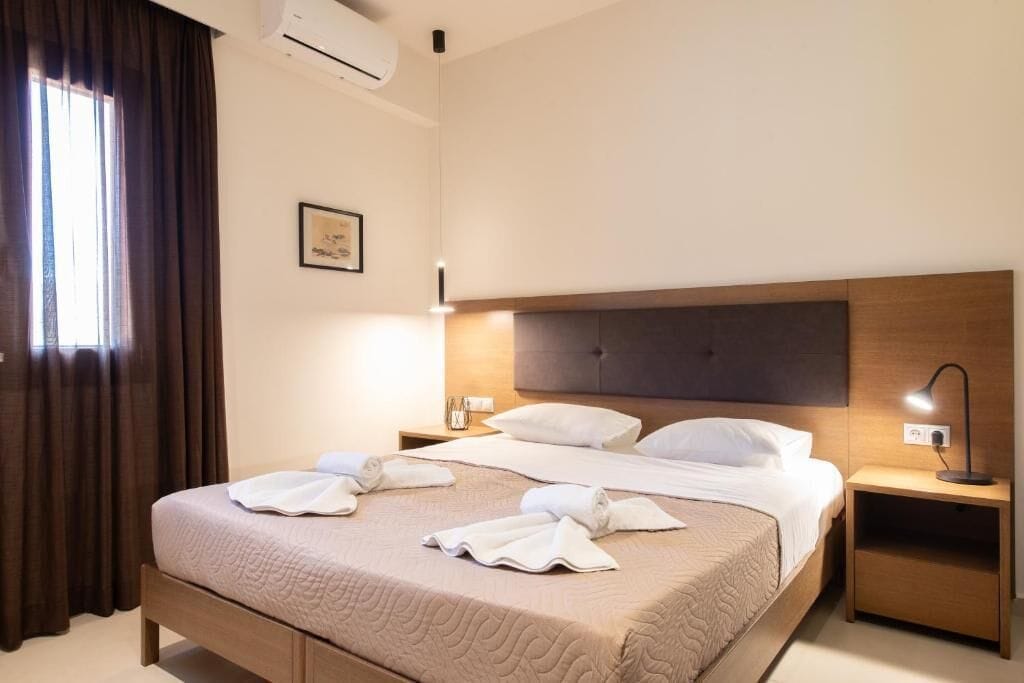 Habitación de hotel con una cama, dos mesitas de noche, una lámpara y un cuadro en la pared.