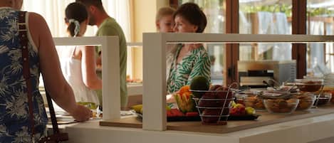 A buffet setup with various food items and a person serving.