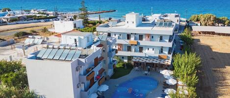 A hotel with multiple floors, a rooftop pool, and a view of the sea.